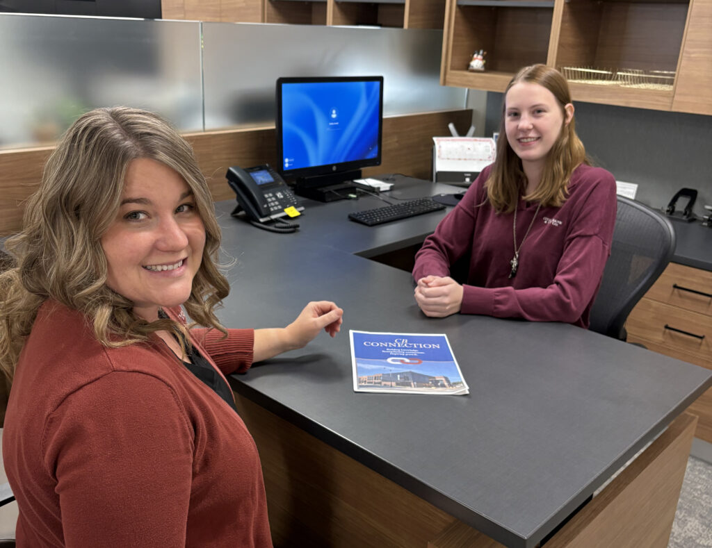 2 Citizens Bank staff members at desk, smiling at camera